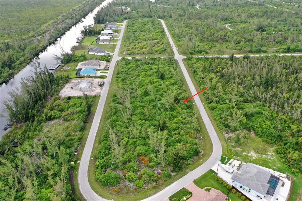 An aerial view shows a vacant, wooded residential lot surrounded by paved roads and houses — 16449 LIGGETT CIRCLE, PORT CHARLOTTE, FL