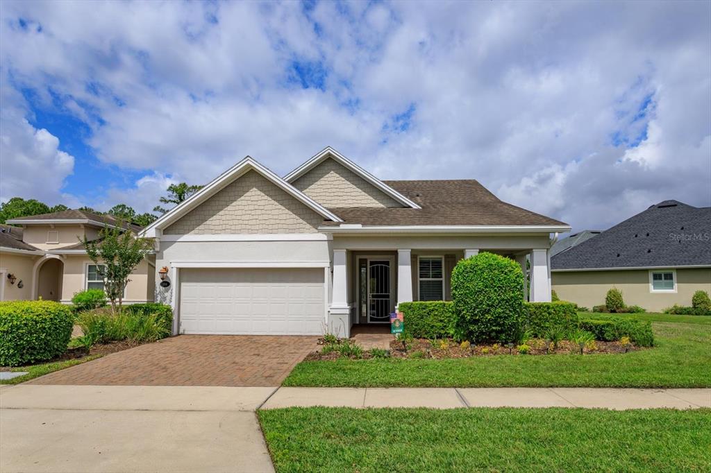 A single-story house with a two-car garage, tan siding, and a covered front porch — 1634 VICTORIA GARDENS DRIVE, DELAND, FL