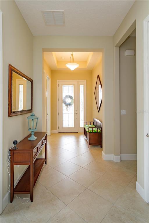 A bright entryway features tile flooring, a wooden console table, and a front door with glass — 1634 VICTORIA GARDENS DRIVE, DELAND, FL