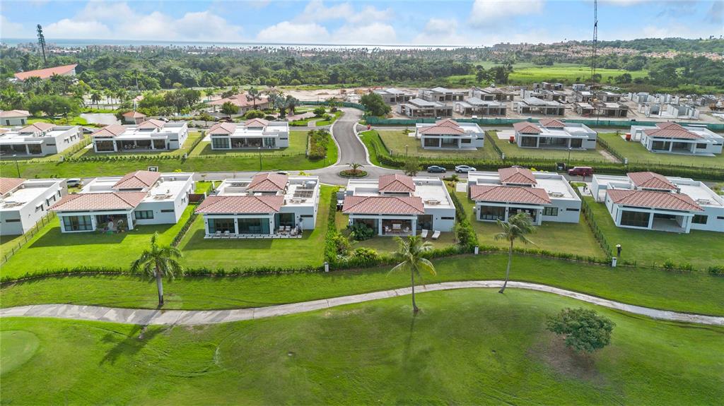 An aerial view shows several modern, single-story houses with tiled roofs bordering a golf course — 49 LOS LAGOS, HUMACAO, PR