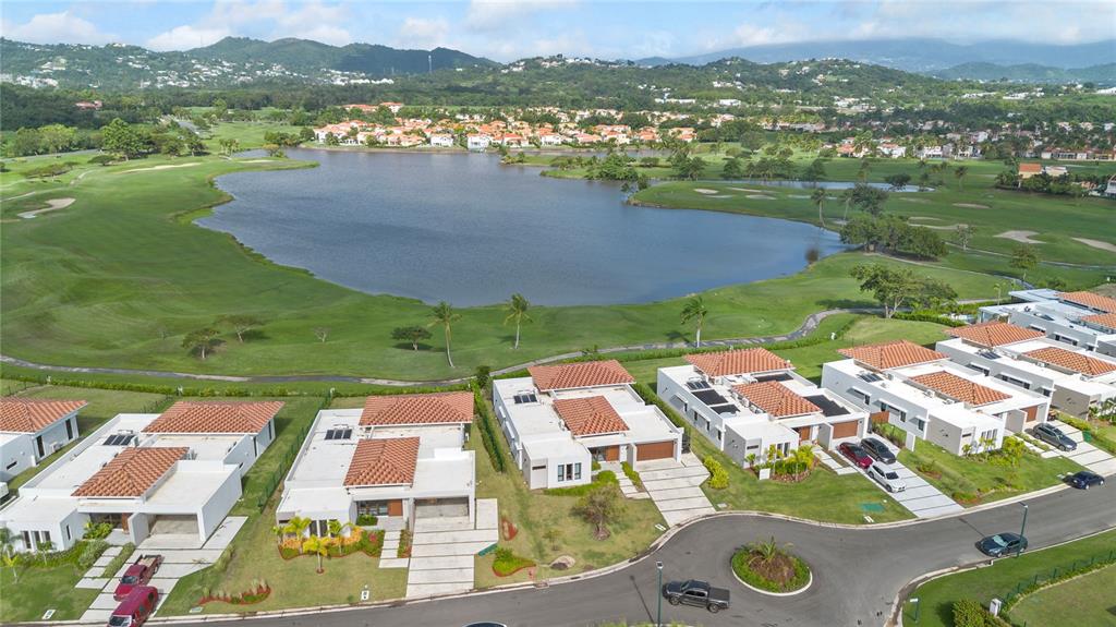 An aerial view shows a row of modern houses overlooking a large lake and golf course — 49 LOS LAGOS, HUMACAO, PR