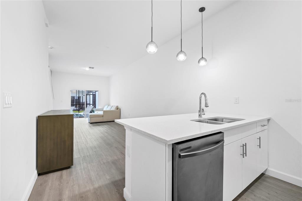 A kitchen island with a sink and dishwasher overlooks a living area with sliding doors — 485 FAMAGUSTA DRIVE, DAVENPORT, FL