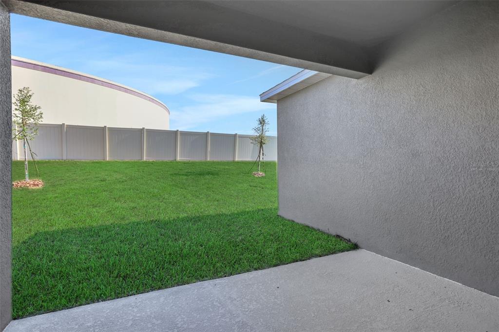 The rear exterior of a single-story house features a gray stucco finish and a concrete patio — 2866 SUPERMARINE ROAD, TAVARES, FL
