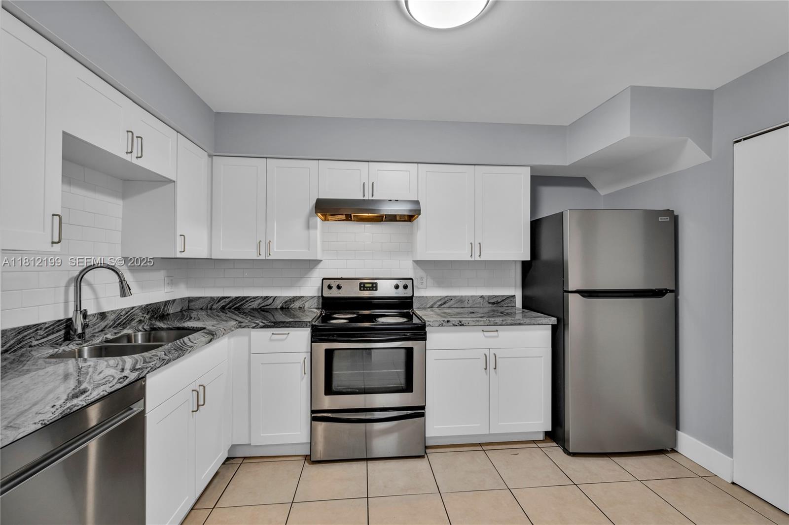 A kitchen features white cabinets, stainless steel appliances, and dark granite countertops — 8109 SW 21 CT # 8109, Miramar FL 33025, MIRAMAR, FL