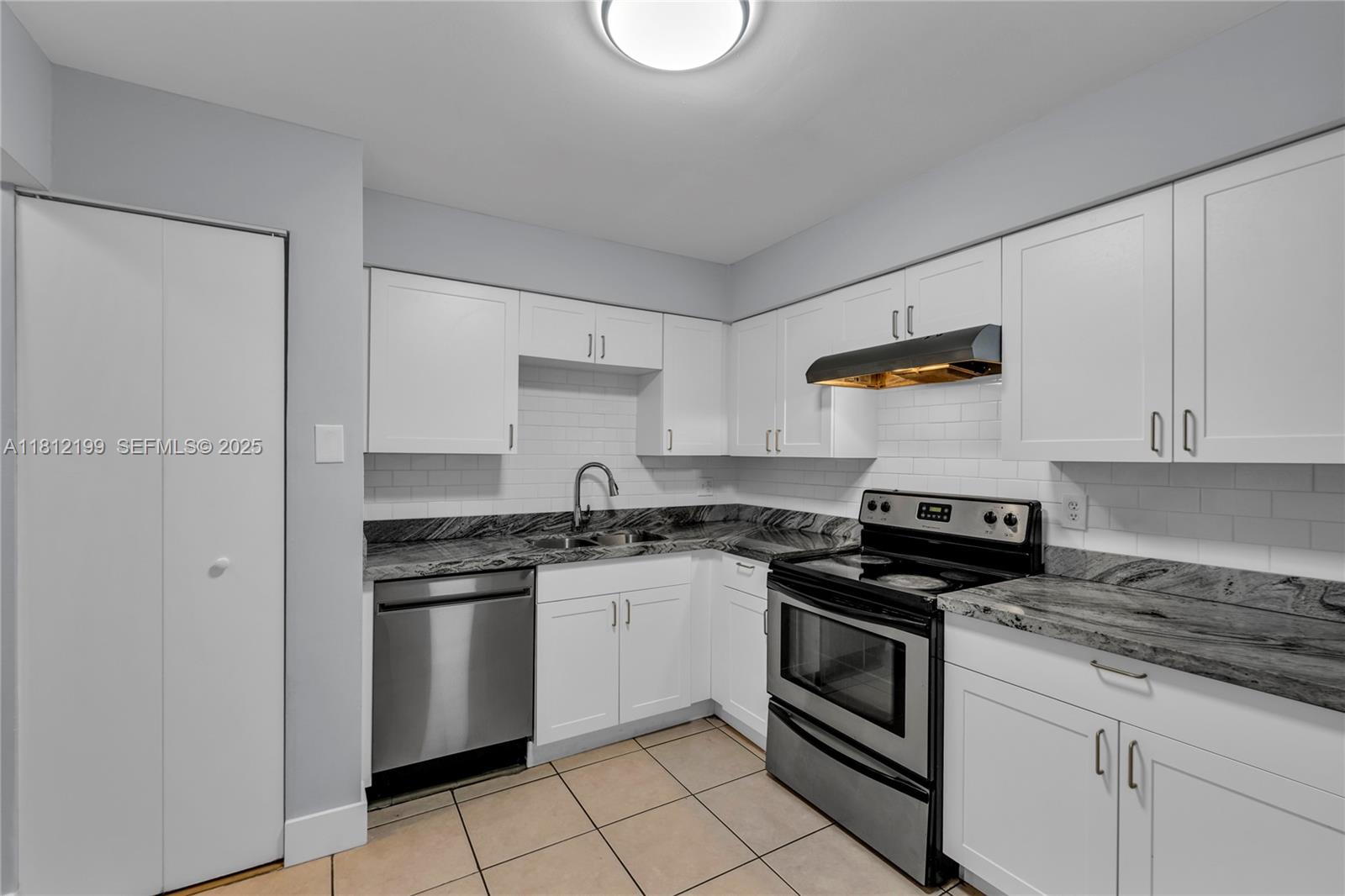A kitchen features white cabinets, stainless steel appliances, and dark granite countertops — 8109 SW 21 CT # 8109, Miramar FL 33025, MIRAMAR, FL