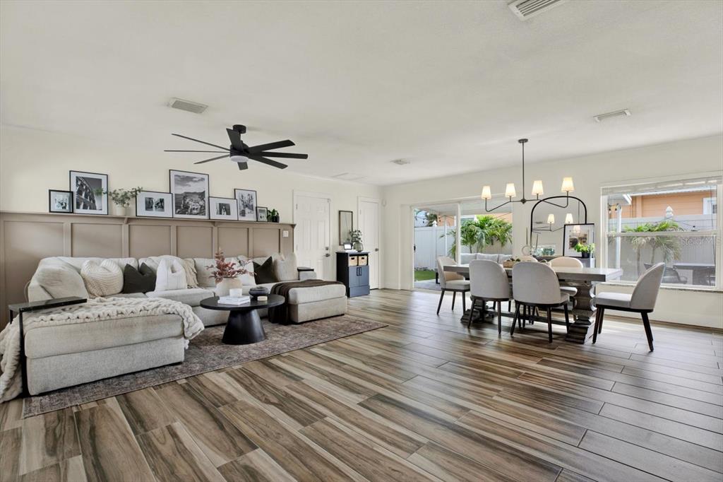 An open-concept living and dining area features wood-look tile flooring and a paneled accent wall — 1308 MARION DRIVE S, ST PETERSBURG, FL