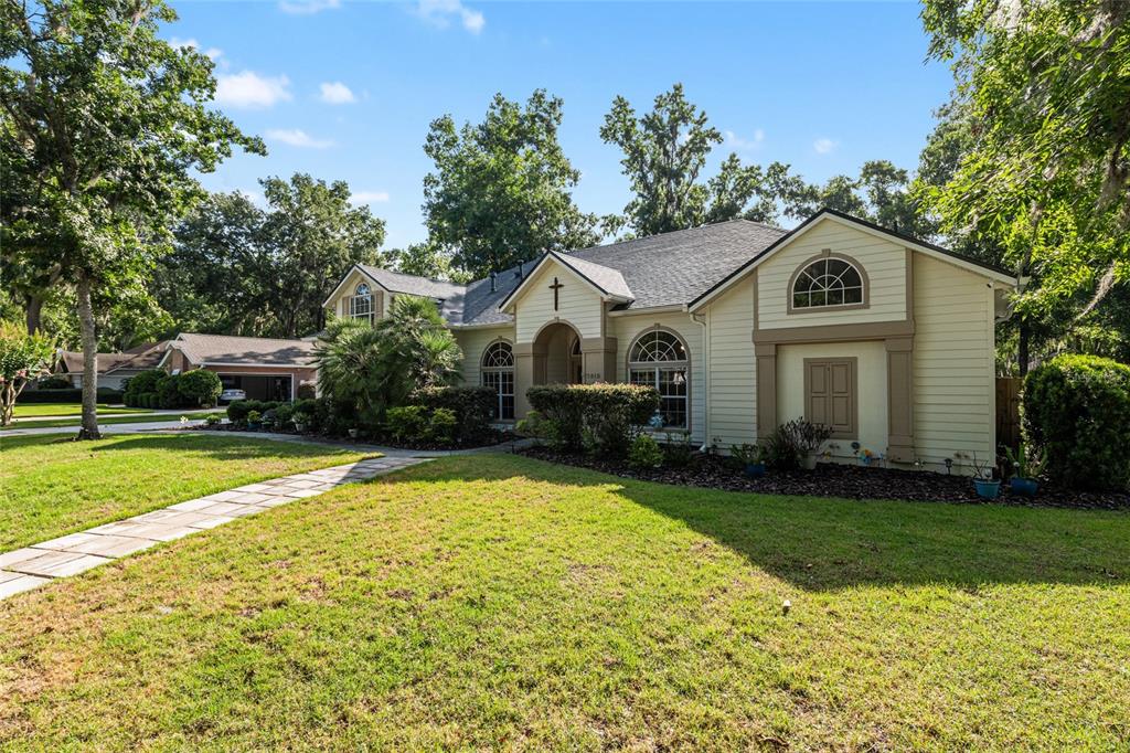 A single-story house with light siding, a cross above the entrance, and a detached garage — 7513 NW 50TH STREET, GAINESVILLE, FL