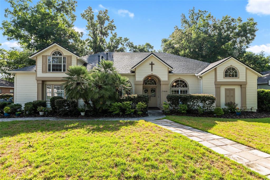 A single-story house with light-colored siding, a stone walkway, and a cross above the entrance — 7513 NW 50TH STREET, GAINESVILLE, FL
