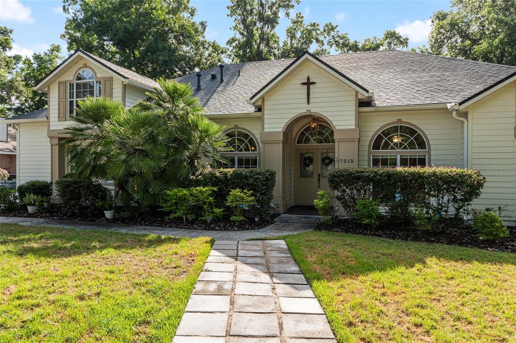 A single-story house with light siding, a cross above the entrance, and a stone walkway — 7513 NW 50TH STREET, GAINESVILLE, FL