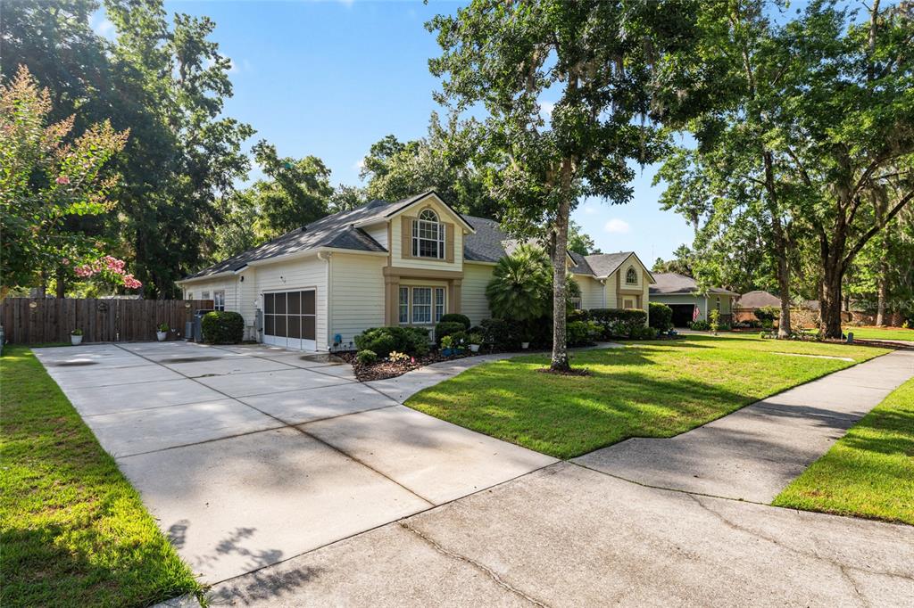 A light-colored house with a large concrete driveway and a spacious front lawn — 7513 NW 50TH STREET, GAINESVILLE, FL