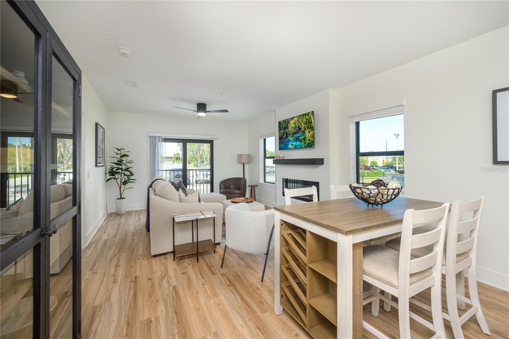 A living and dining area features light wood floors, a fireplace, and a kitchen island — 415 SE 1ST AVENUE UNIT 103, OCALA, FL