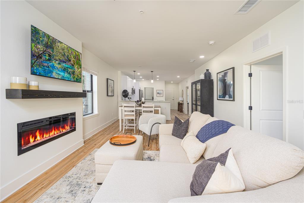 A living room features a fireplace, wall-mounted television, sectional sofa, and an adjacent dining area — 415 SE 1ST AVENUE UNIT 103, OCALA, FL