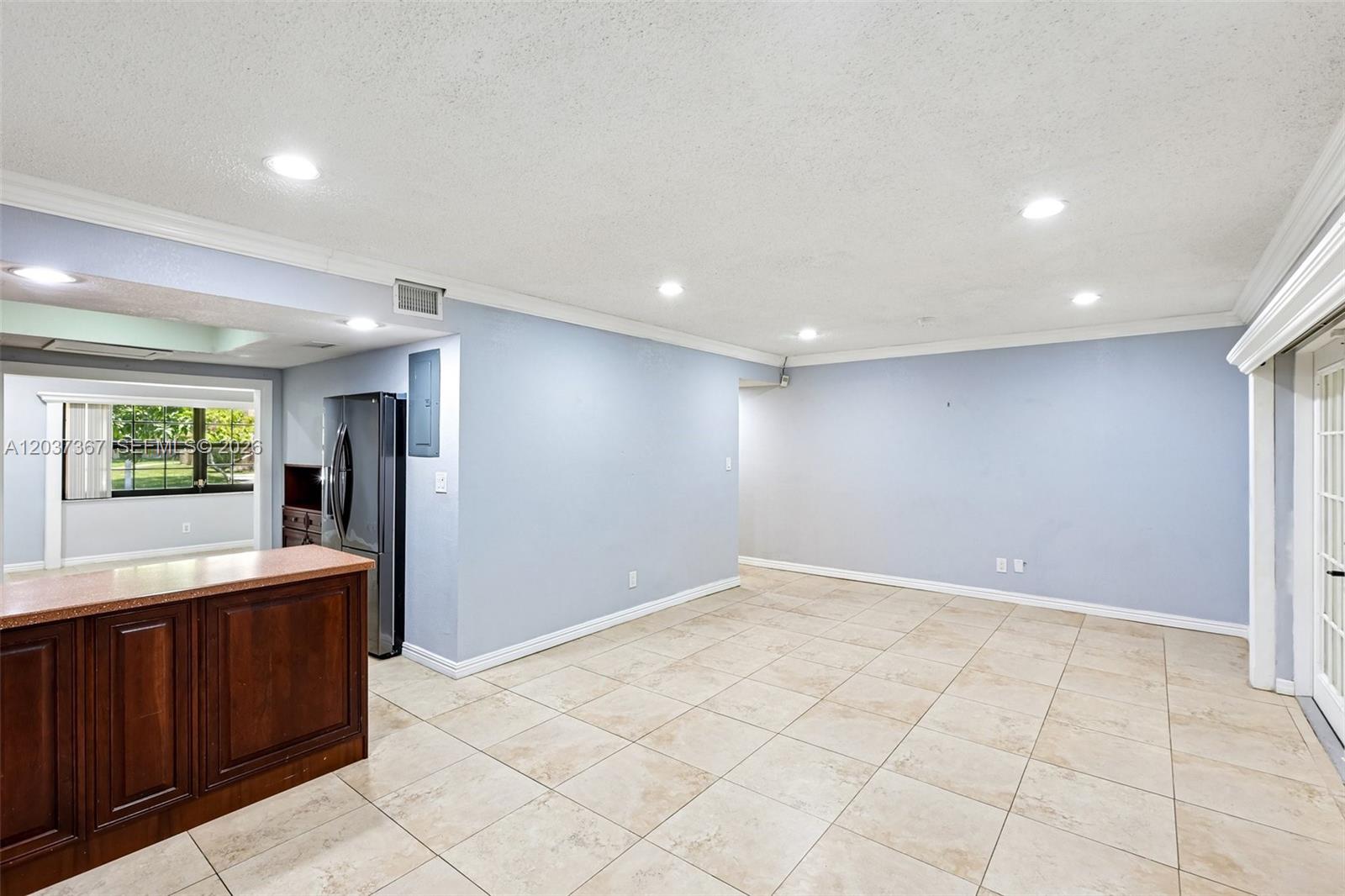 A spacious room features light blue walls, tan tile flooring, and a dark wood island — 86 Ann Lee Ln, Tamarac FL 33319, TAMARAC, FL