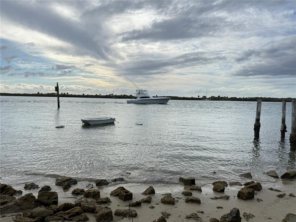 A white boat travels across a waterway near a rocky shoreline and wooden pilings — 1602 N INDIAN RIVER ROAD, NEW SMYRNA BEACH, FL
