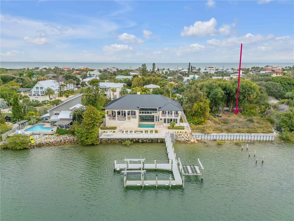 An aerial view shows a waterfront house with a private dock and an adjacent lot — 1602 N INDIAN RIVER ROAD, NEW SMYRNA BEACH, FL