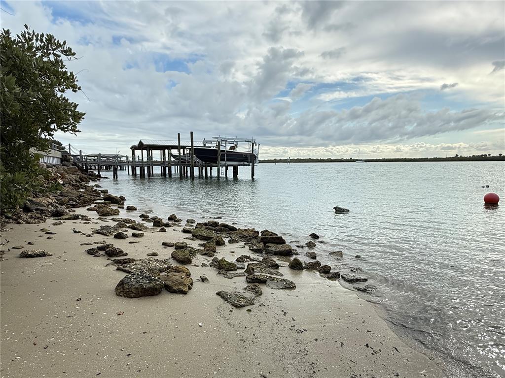 A boat lift sits at the end of a wooden dock along a rocky shoreline — 1602 N INDIAN RIVER ROAD, NEW SMYRNA BEACH, FL