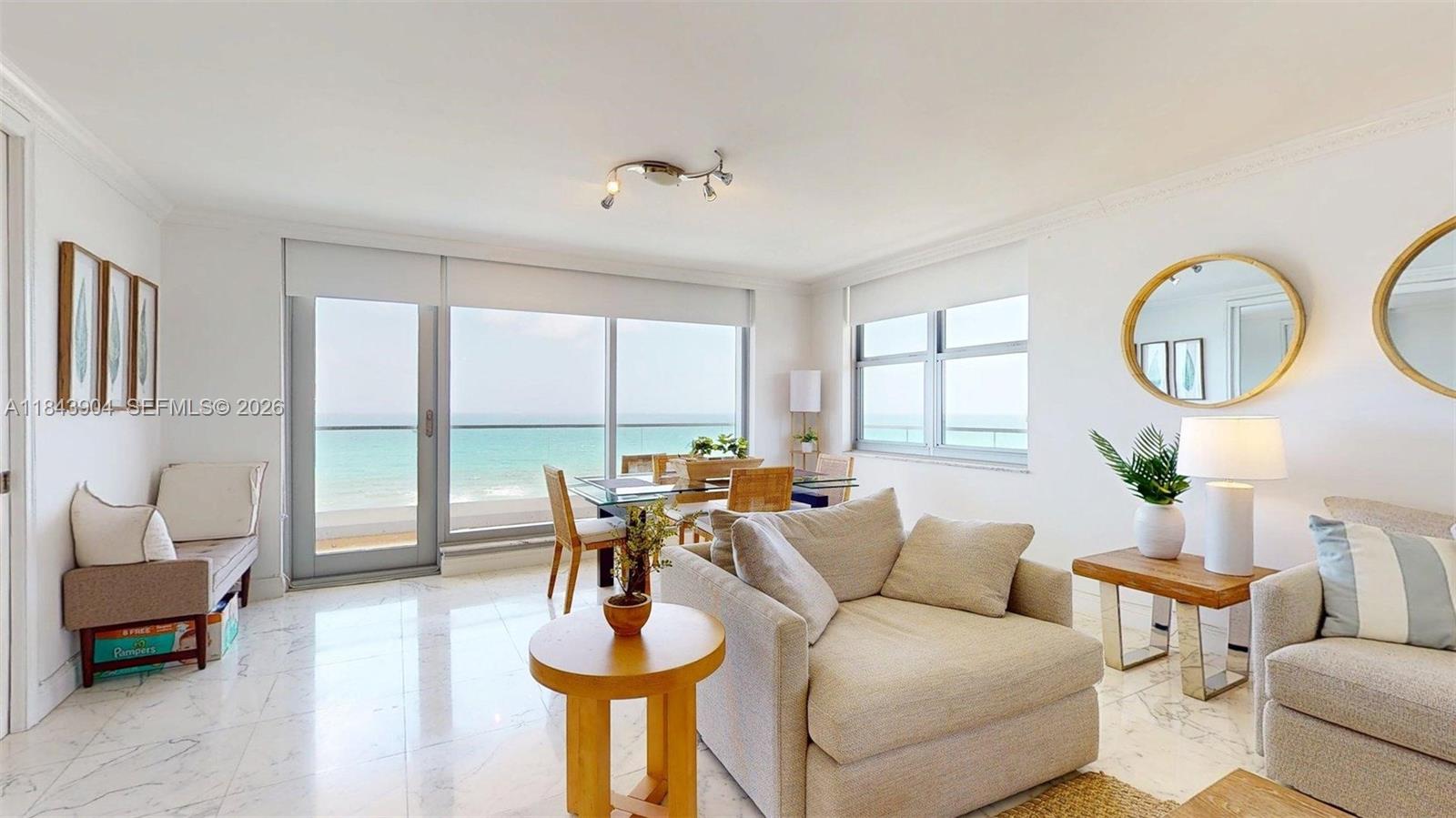 A bright living and dining area features marble floors, neutral furniture, and ocean views — 1912 S Ocean Dr # 9A, Hallandale Beach FL 33009, HALLANDALE BEACH, FL