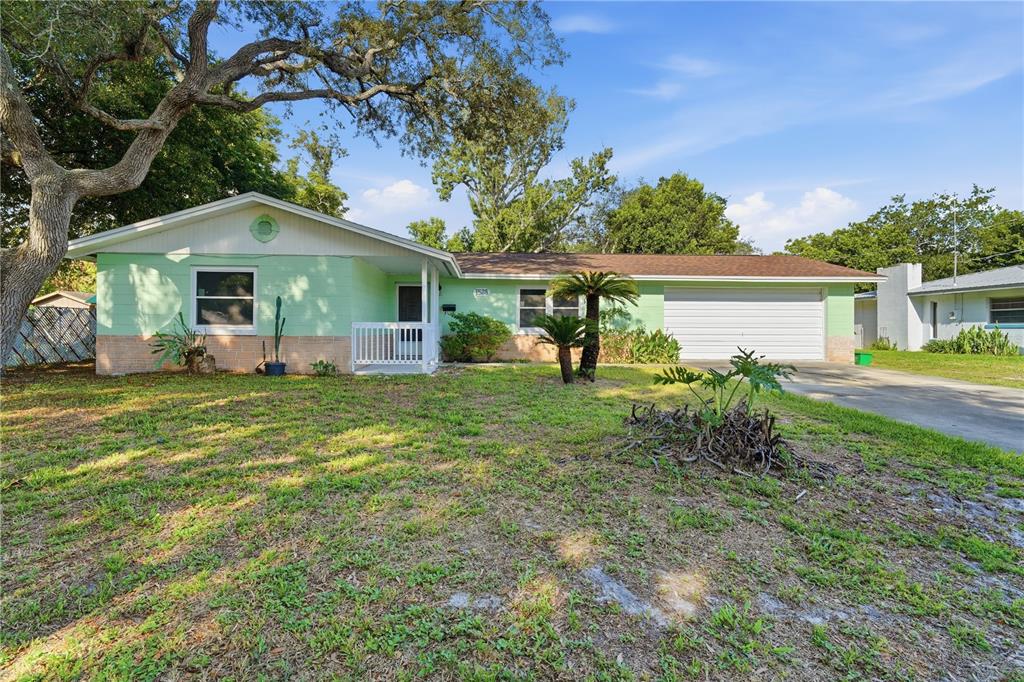 A single-story house with light green siding, a brick base, and an attached two-car garage — 1528 VALENCIA AVENUE, DAYTONA BEACH, FL