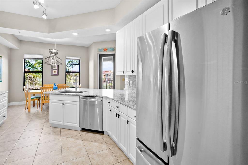 A kitchen features white cabinets, granite countertops, stainless steel appliances, and an adjacent dining area — 98 VIVANTE BOULEVARD UNIT 410, PUNTA GORDA, FL