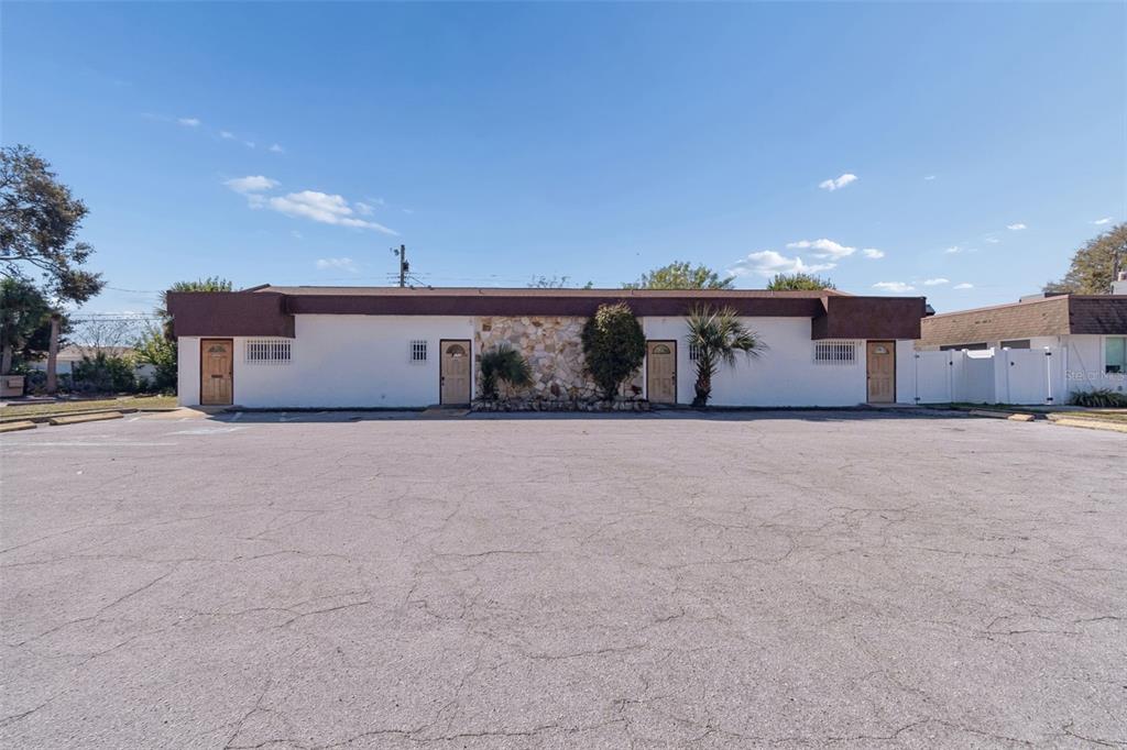 A single-story building with four exterior doors and a stone facade section faces a parking lot — 1152 62ND AVENUE S, ST PETERSBURG, FL