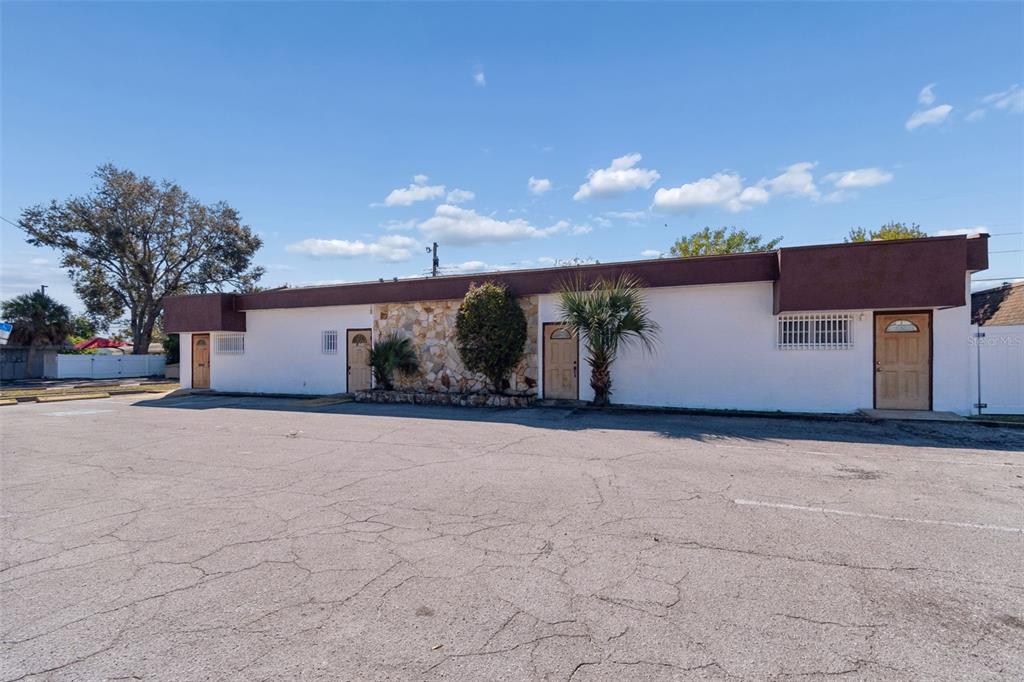 A single-story commercial building with a white stucco facade, stone accents, and four entry doors — 1152 62ND AVENUE S, ST PETERSBURG, FL