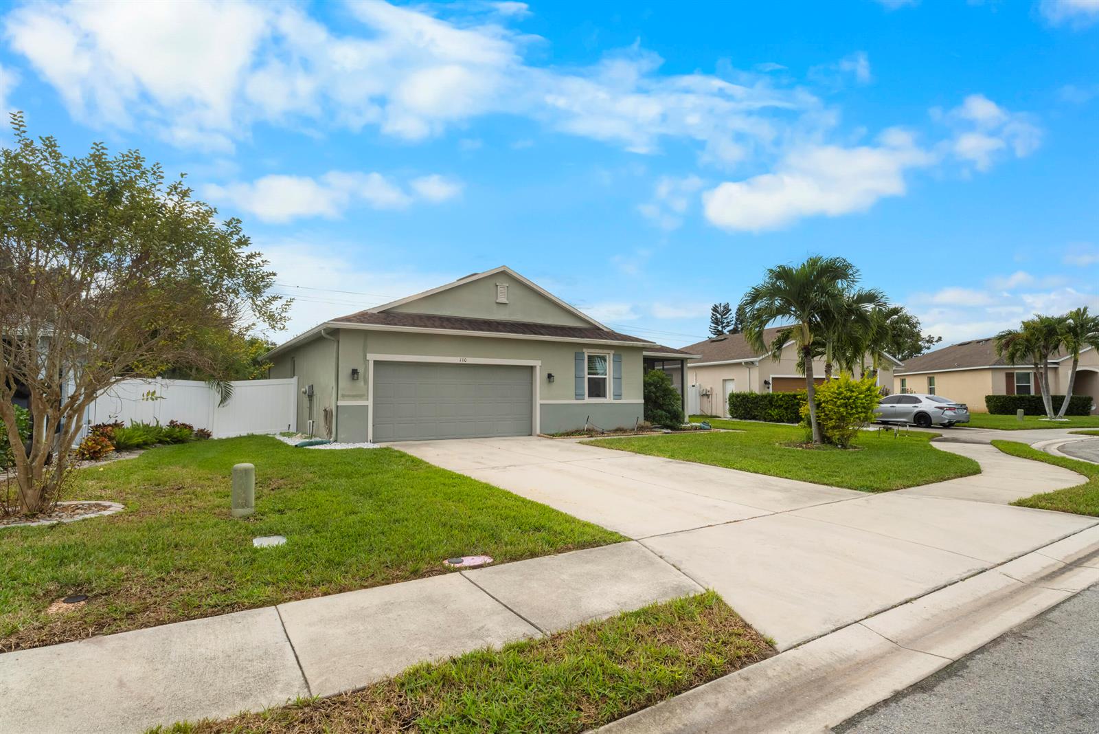 A single-story house with a two-car garage, a concrete driveway, and a green lawn — 110 65th Avenue E, Bradenton FL 34203, BRADENTON, FL