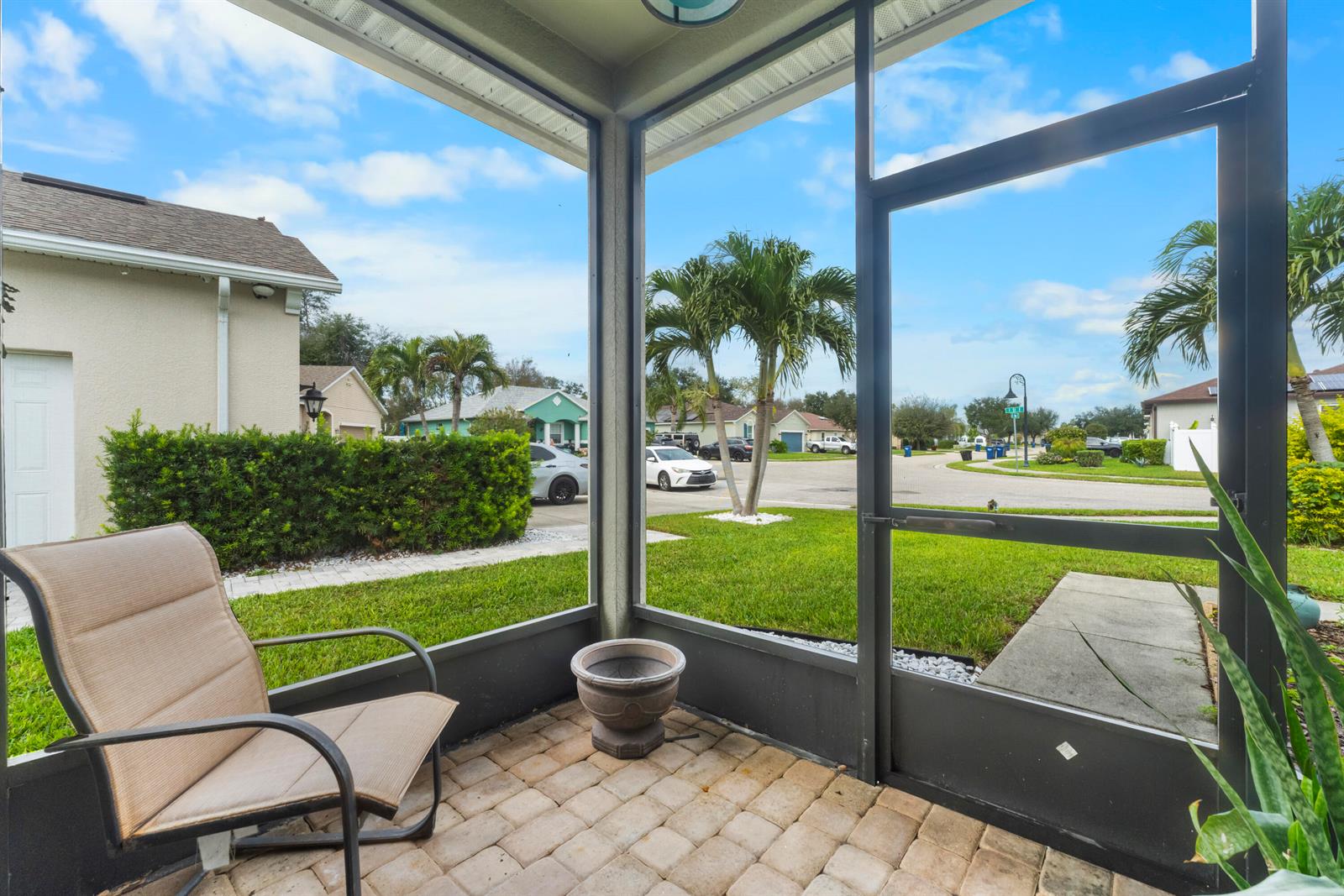 A screened-in patio features a tan chair, a stone planter, and views of a neighborhood — 110 65th Avenue E, Bradenton FL 34203, BRADENTON, FL
