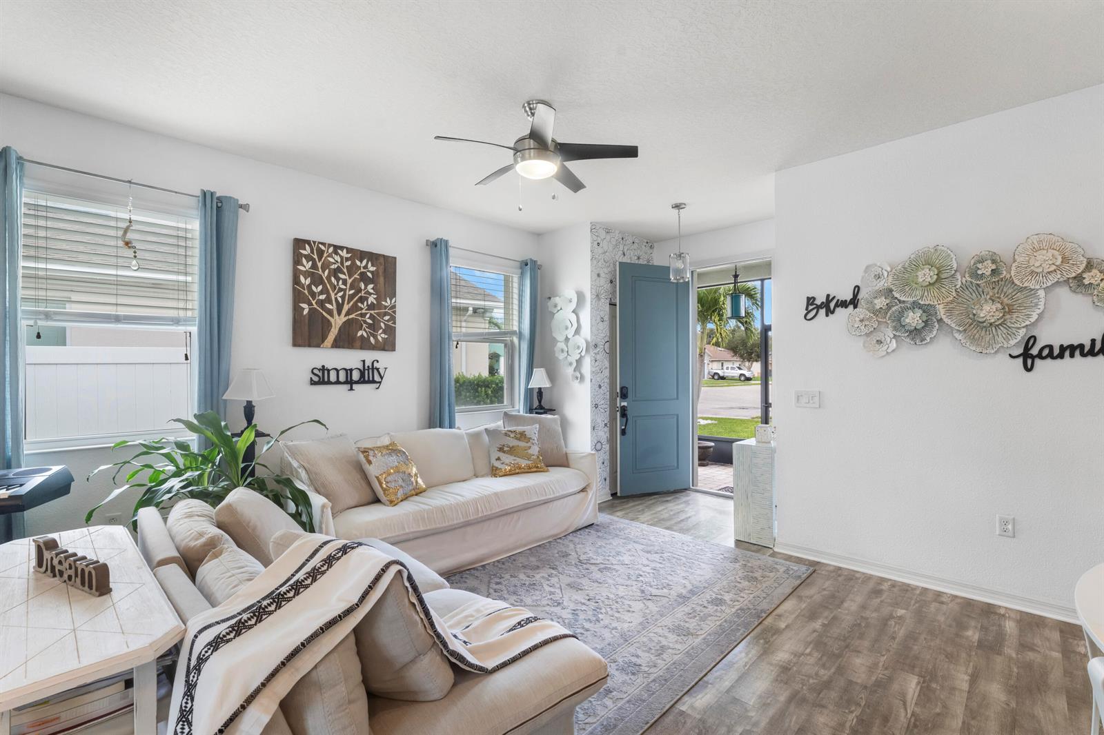 A bright living room features a white sofa, blue front door, and patterned area rug — 110 65th Avenue E, Bradenton FL 34203, BRADENTON, FL
