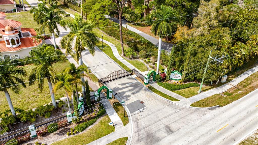 An aerial view shows the gated entrance to a residential community with palm trees — 1680 ASSISI DRIVE UNIT 13, SARASOTA, FL