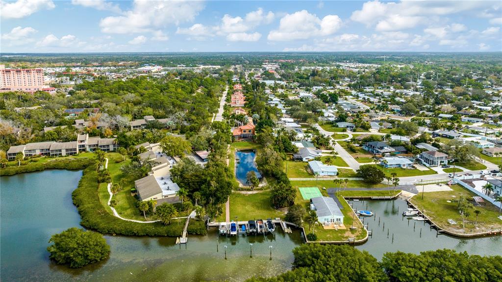 An aerial view shows a residential waterfront community with boat docks, a pond, and buildings — 1680 ASSISI DRIVE UNIT 13, SARASOTA, FL