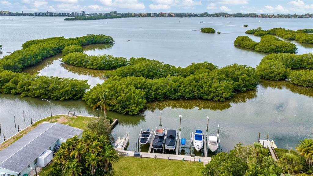 An aerial view shows a boat dock with several vessels next to a grassy shoreline — 1680 ASSISI DRIVE UNIT 13, SARASOTA, FL