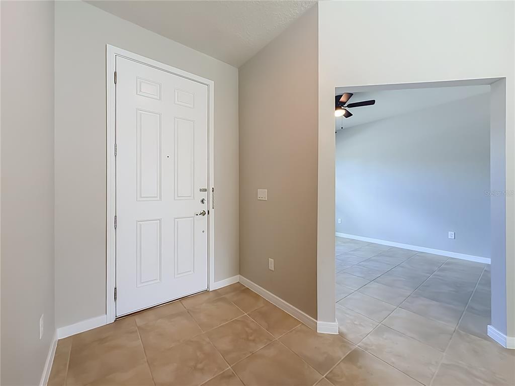 A tiled entryway features a white front door and an open archway to a room — 5729 WOODEN PINE DRIVE, ORLANDO, FL