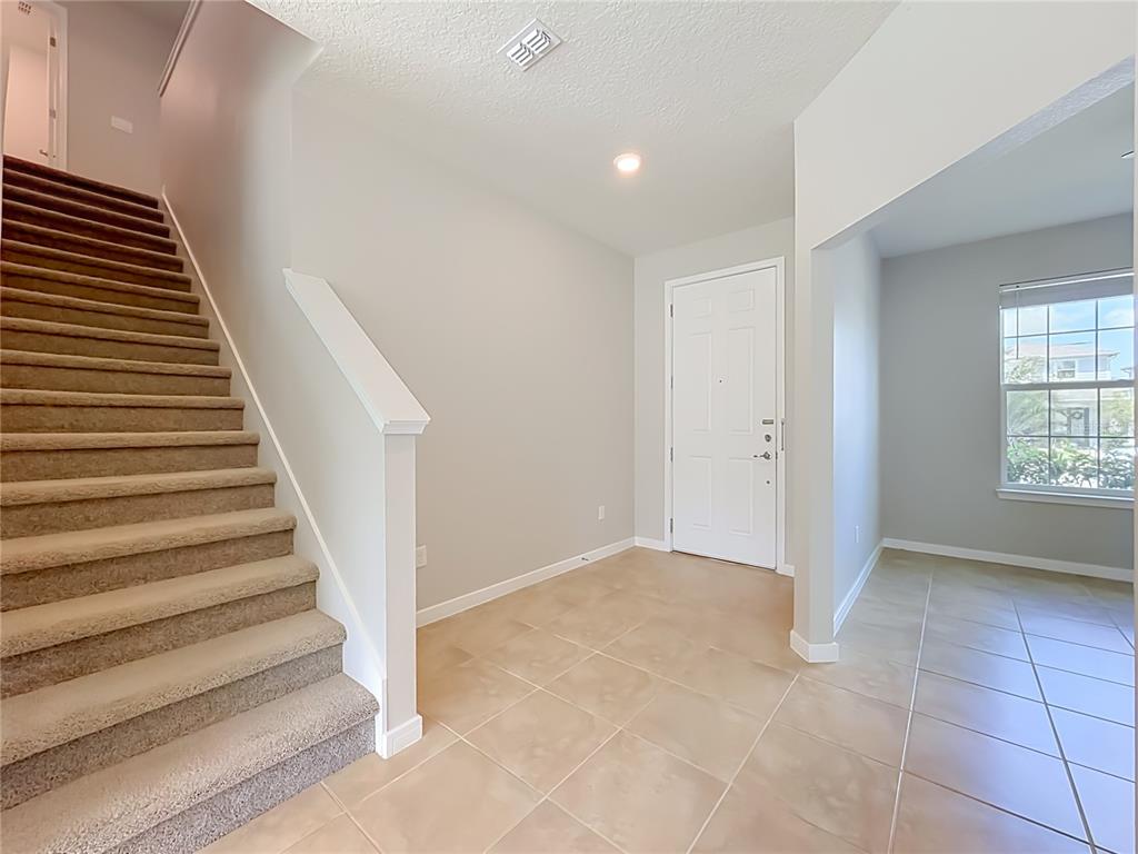 An entryway features a carpeted staircase, tile flooring, a white front door, and a window — 5729 WOODEN PINE DRIVE, ORLANDO, FL