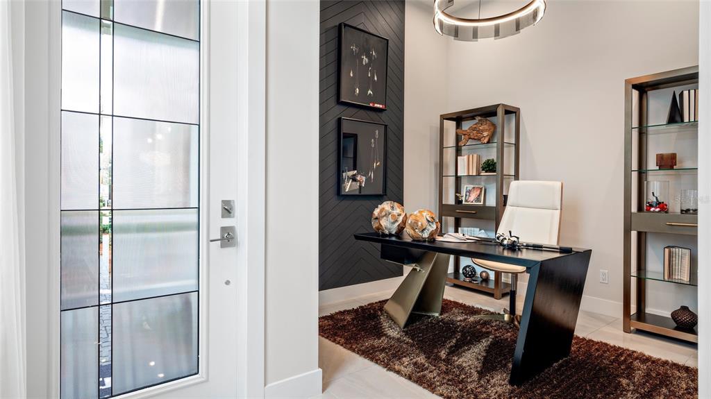 A modern home office features a dark chevron accent wall, a glass-topped desk, and shelving — 1230 TRIDENT LOOP, DELAND, FL