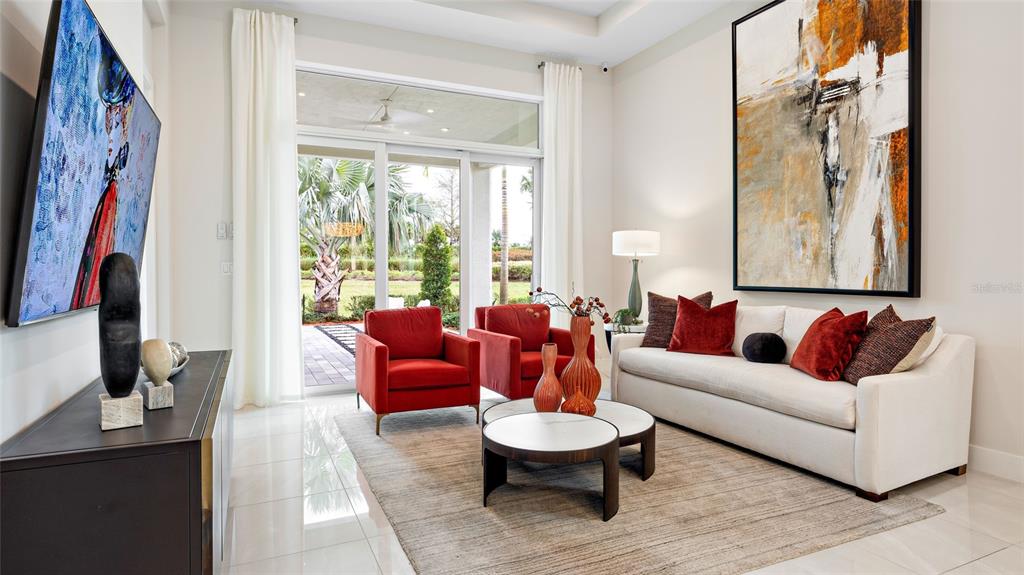 A bright living room features red armchairs, a white sofa, and a large abstract painting — 1230 TRIDENT LOOP, DELAND, FL