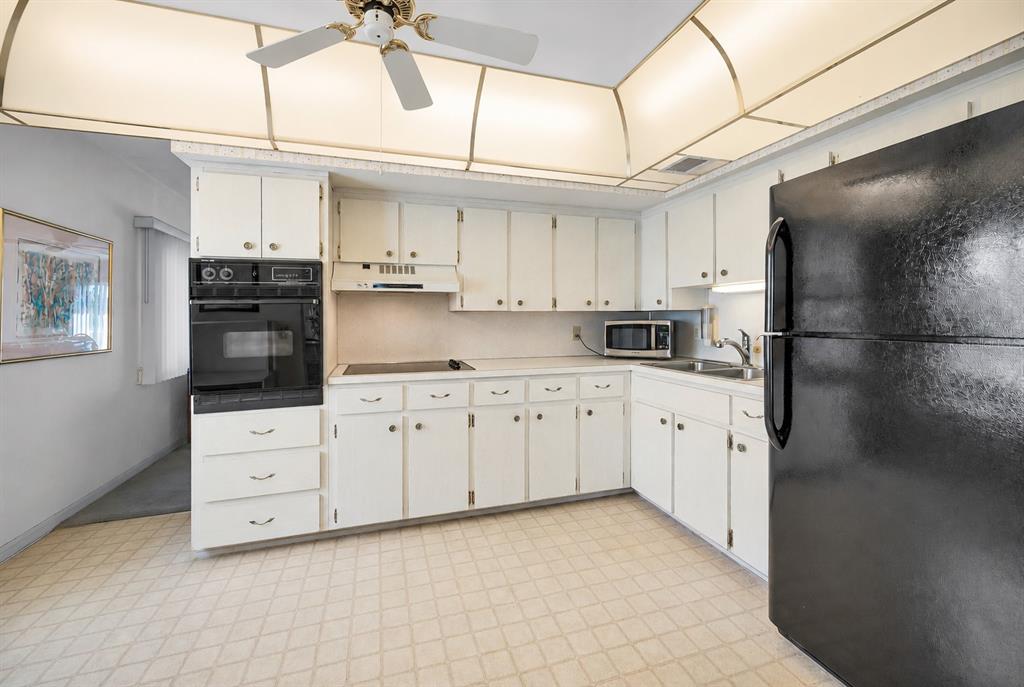 A kitchen features white cabinets, black appliances, a drop-in cooktop, and a recessed ceiling light — 2001 WORLD PARKWAY BOULEVARD UNIT 39, CLEARWATER, FL