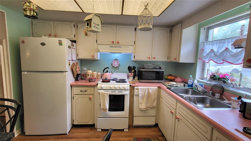 A kitchen features white cabinets, pink countertops, a white stove, and a white refrigerator — 1421 NORMANDY PARK DRIVE UNIT 4, CLEARWATER, FL