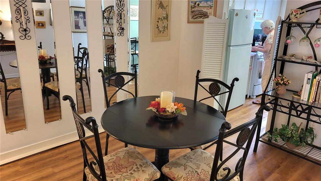 A dining area features a round black table with four chairs and mirrored wall panels — 1421 NORMANDY PARK DRIVE UNIT 4, CLEARWATER, FL