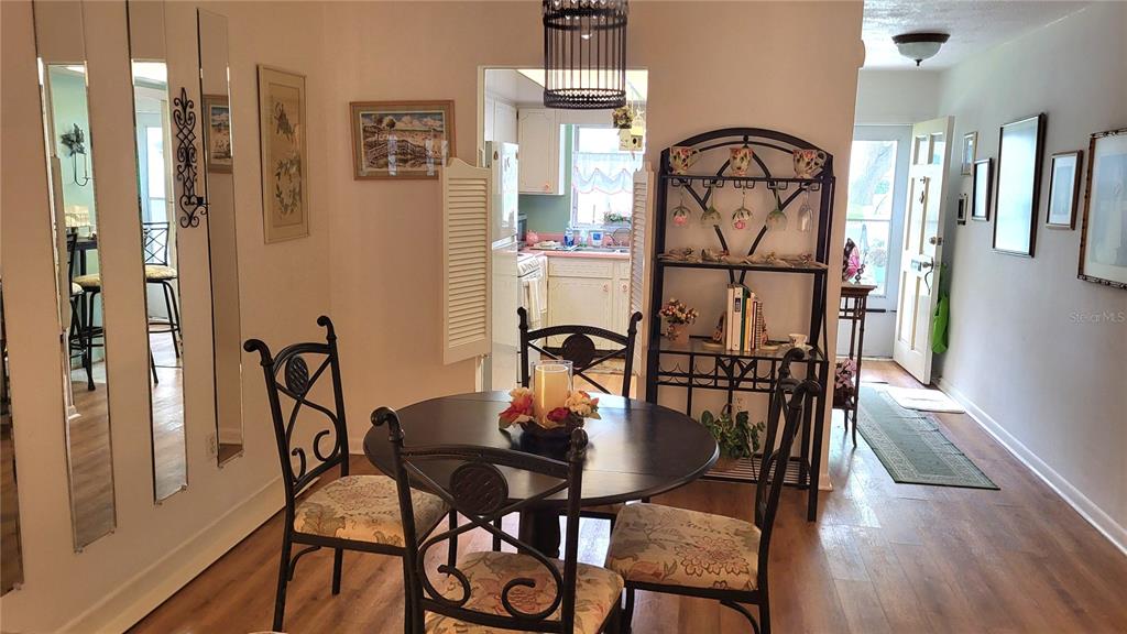 A dining area features a round table with chairs, a metal shelf, and wood flooring — 1421 NORMANDY PARK DRIVE UNIT 4, CLEARWATER, FL