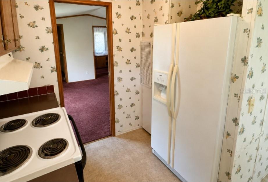 A kitchen with floral wallpaper, a white electric stove, and a white side-by-side refrigerator — 1142 SW JIM CLARK ROAD, MADISON, FL