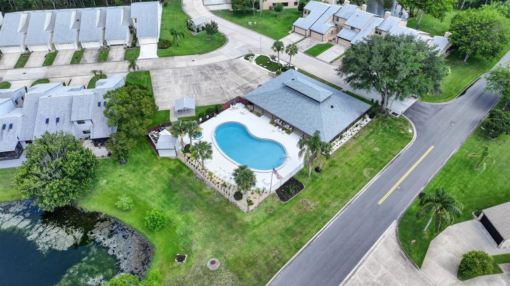 An aerial view shows a community swimming pool and clubhouse surrounded by townhomes and landscaping — 357 CASTLEWOOD LANE, NEW SMYRNA BEACH, FL