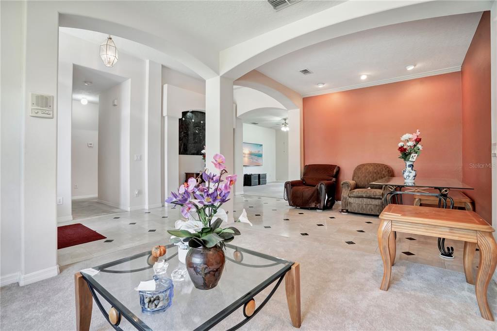 An open-concept living and dining area features tile and carpet flooring with arched architectural details — 1709 GOLFVIEW DRIVE, KISSIMMEE, FL