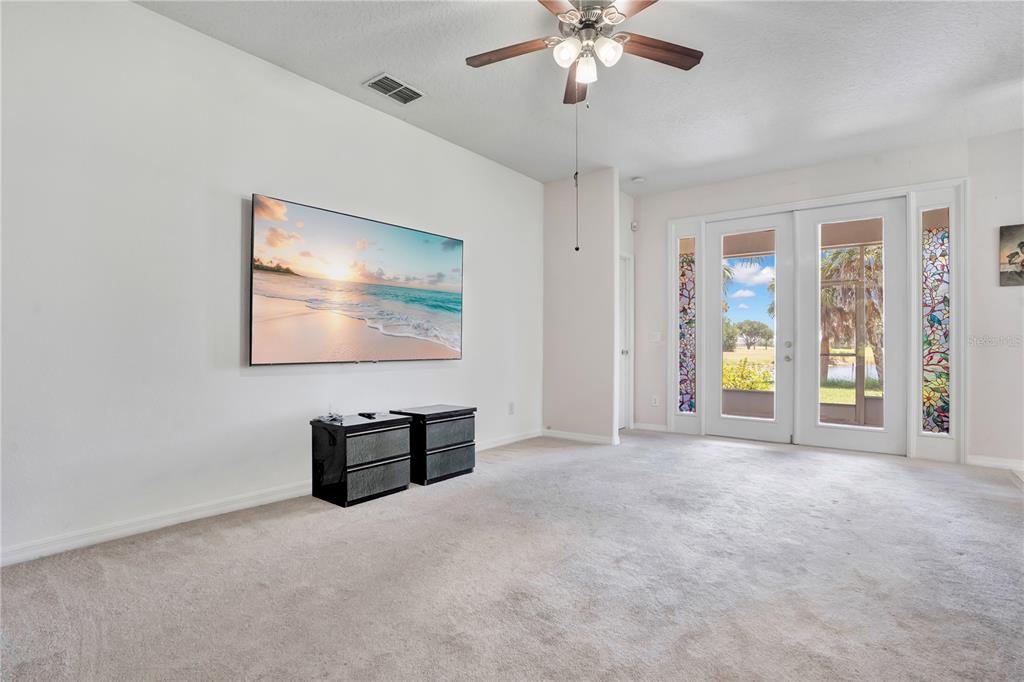 A living room features a wall-mounted television, two black cabinets, and glass-paned double doors — 1709 GOLFVIEW DRIVE, KISSIMMEE, FL