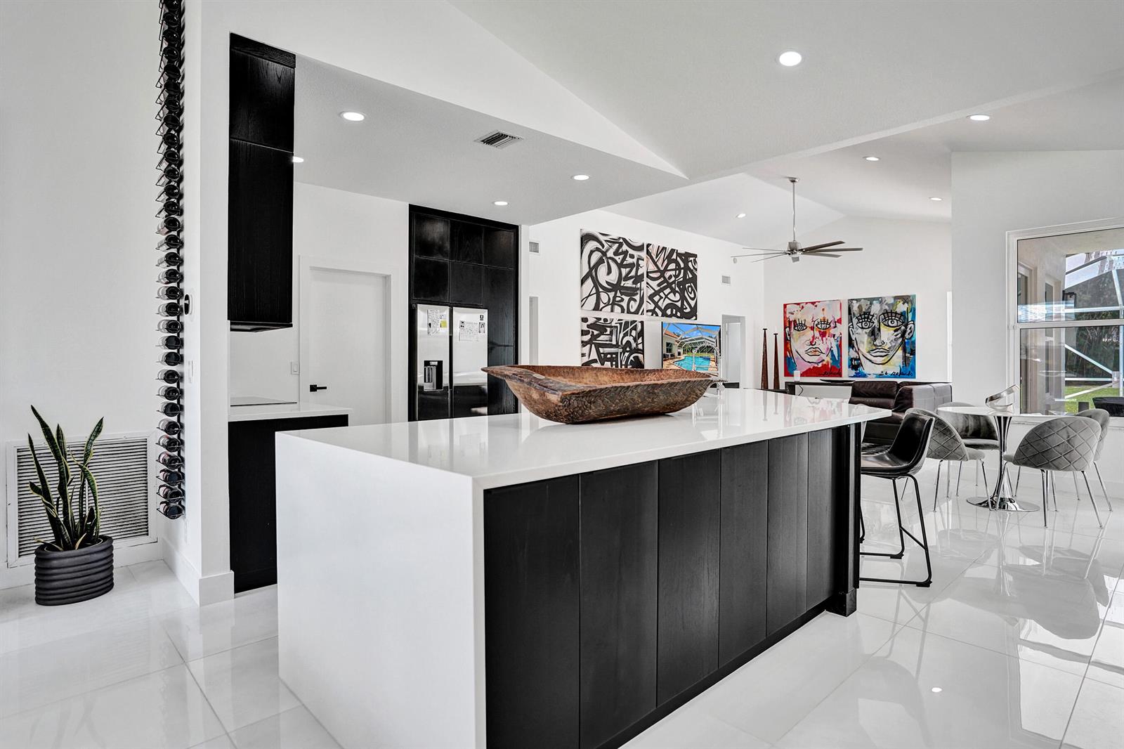 A modern kitchen features a large white-topped island with black cabinetry and abstract wall art — 4300 Hunting Trail, Lake Worth FL 33467, LAKE WORTH, FL