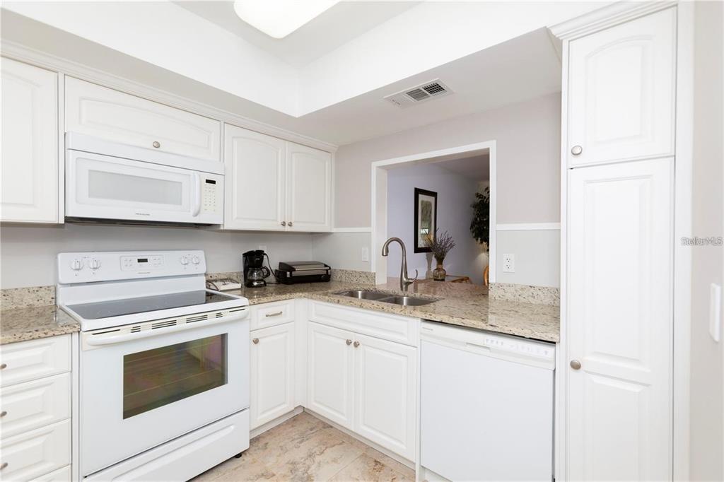 A kitchen with white cabinets, granite countertops, and white appliances — 4632 MARINE PARKWAY UNIT 201, NEW PORT RICHEY, FL