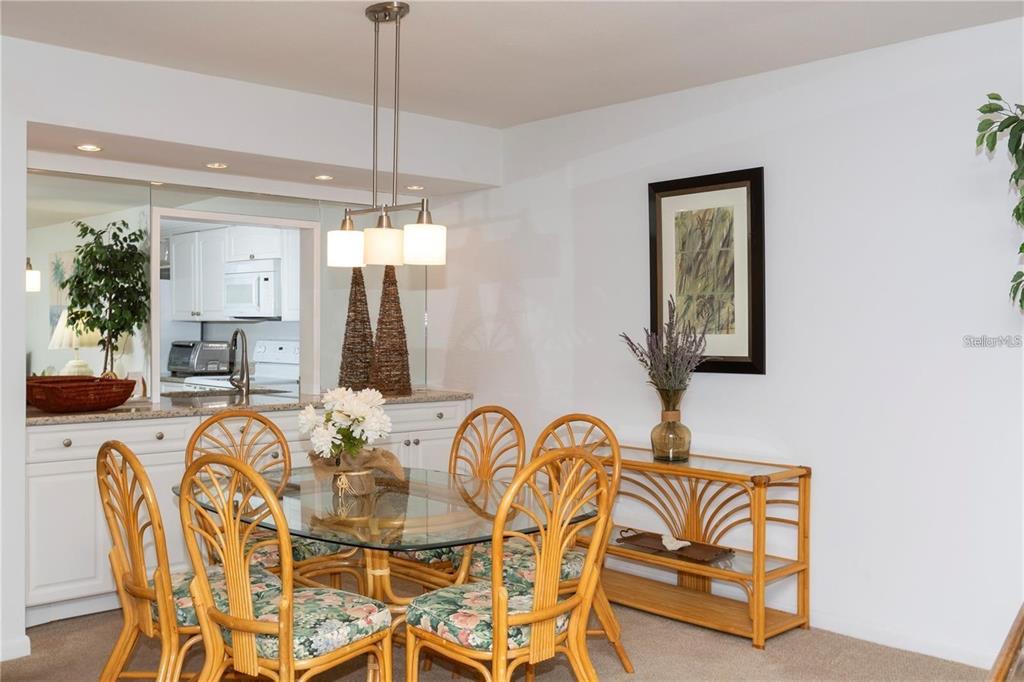A dining room features a glass-topped rattan table, matching chairs, and a console table — 4632 MARINE PARKWAY UNIT 201, NEW PORT RICHEY, FL