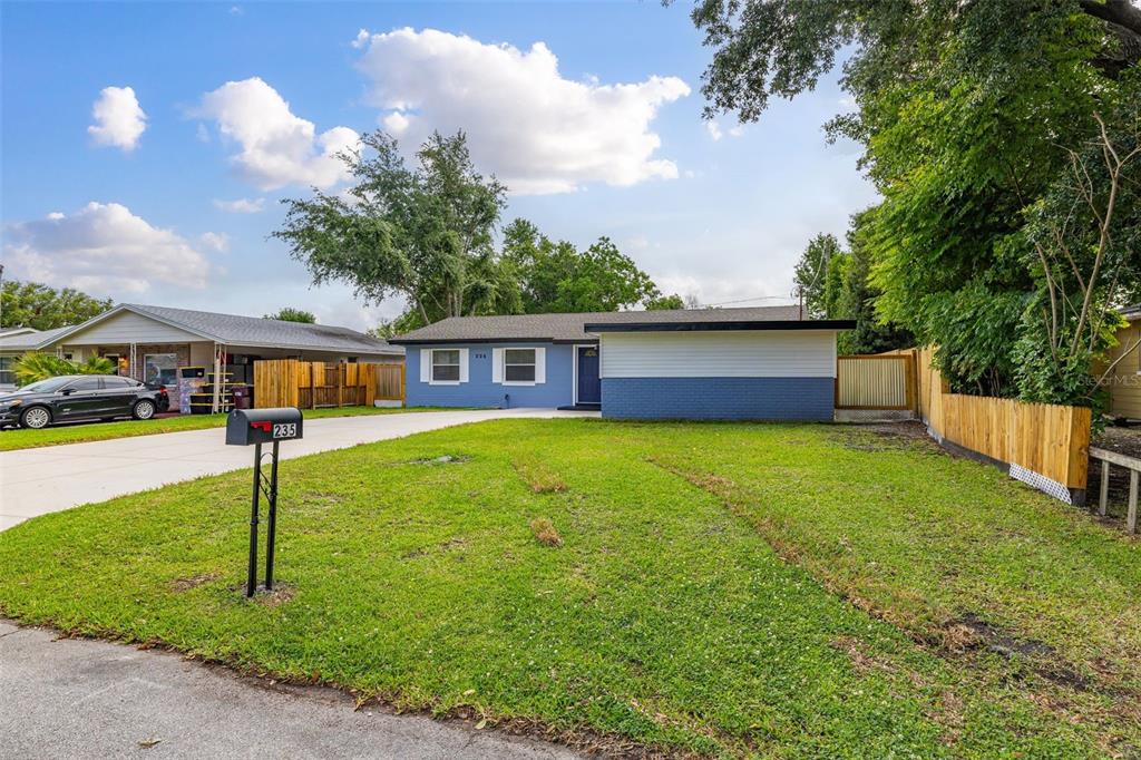 A blue single-story house with a white upper facade and a large front lawn — 235 TENNESSEE AVENUE, ST CLOUD, FL