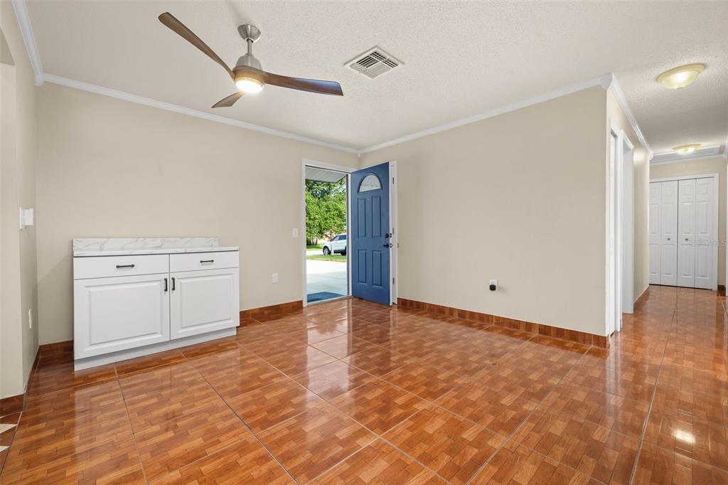 A room with brown tiled flooring, a white cabinet, a ceiling fan, and a blue door — 235 TENNESSEE AVENUE, ST CLOUD, FL