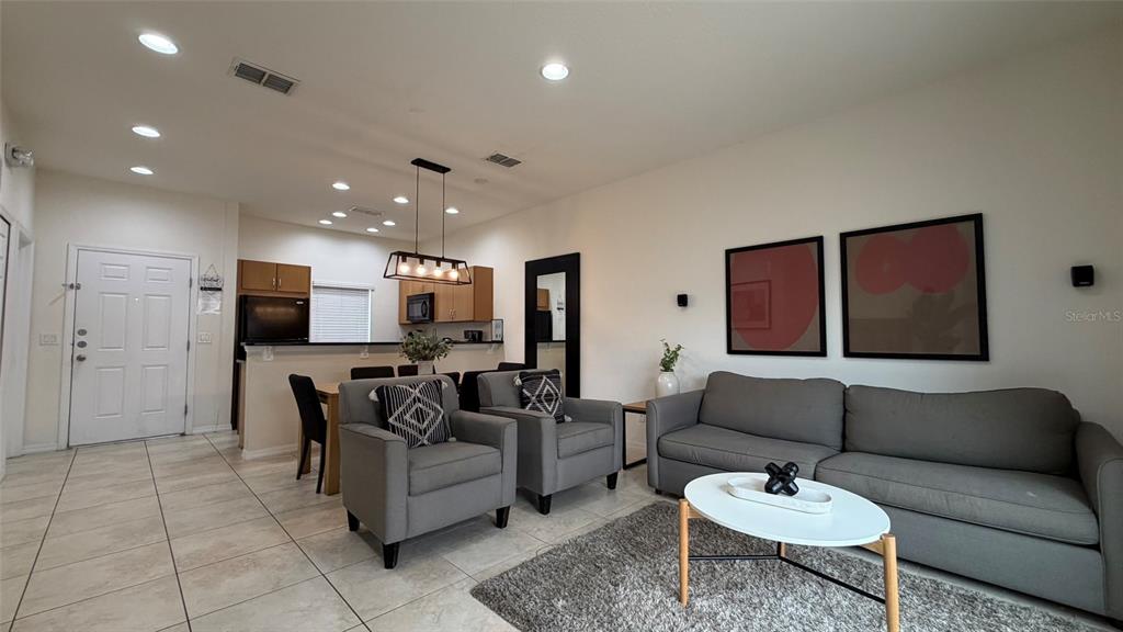 A living room and dining area feature tile flooring, gray furniture, and a kitchen island — 3021 RED GINGER ROAD, KISSIMMEE, FL