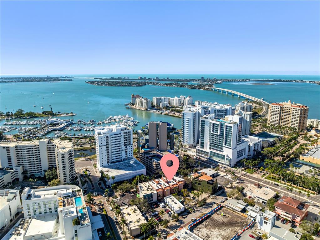 An aerial view shows a coastal city with high-rise buildings, a marina, and a bridge — 1221 N PALM AVENUE UNIT 202, SARASOTA, FL